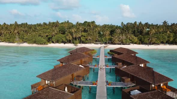 Tourists Walking On Boardwalk Along Water Bungalow By The Sea At An Exotic Resort In Meeru Island, M