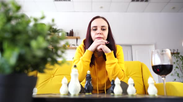 Young Woman Playing Chess and Drinking Red Wine in Room