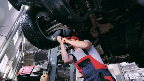 Male Auto Mechanic Tightens a Wheel with a Wrench