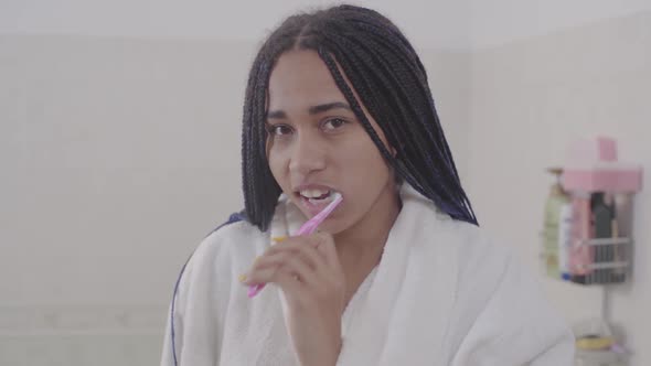 Portrait of Young African American Woman with Dreadlocks Brushing Teeth. Cute Teenage Girl Getting