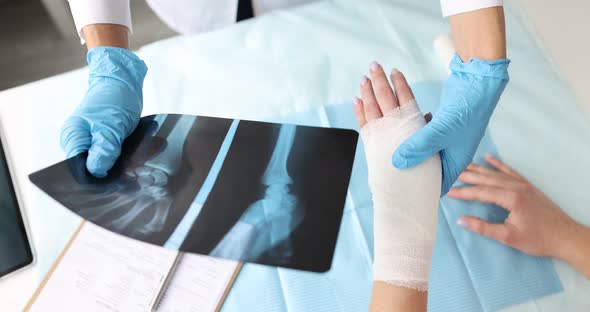Doctor Holds Xray of Hand and Examines Patient Sore Arm