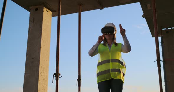 A Woman Engineer at a Construction Site in Virtual Reality Glasses Moves Her Hands Simulating the