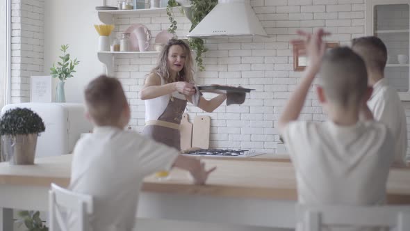 Portrait Young Pretty Mother Bakes Pies for Her Four Teen Sons in White Shirts Waiting for the Food