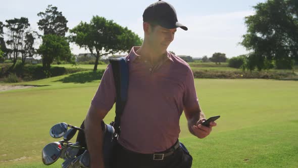 Caucasian male golfer using his smartphone on a golf course