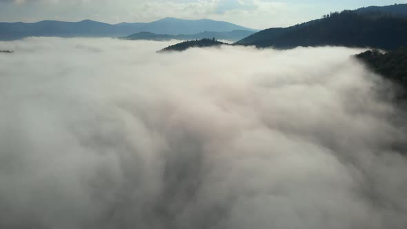 Aerial drone shot of amazing dense fog above river between mountains.