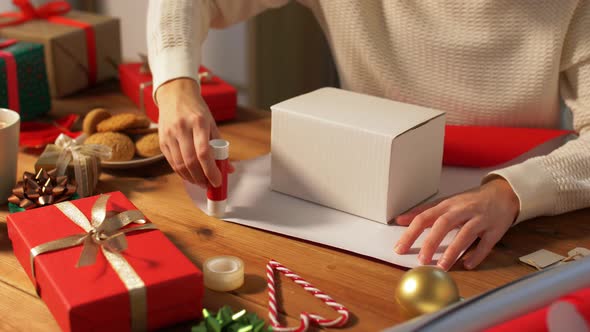 Woman Wrapping Christmas Gift Into Paper at Home