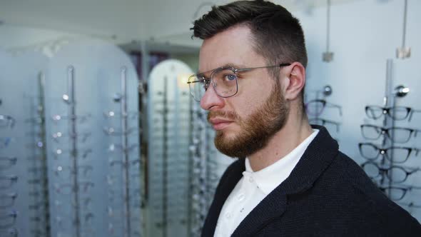 Man Trying Eyeglasses In Optics Store.