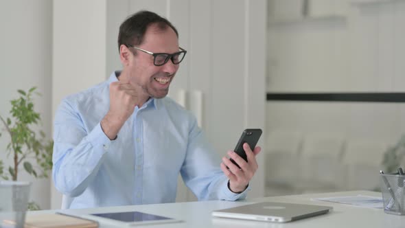 Successful Middle Aged Man Celebrating on Smartphone