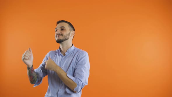 Cheerful Young Man Presenting To the Side, Pointing with Fingers and Dancing Slowly