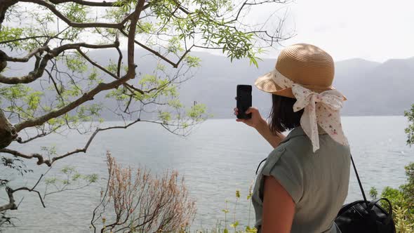 Tourist with beautiful straw hat taking pictures of the famous lake maggiore.