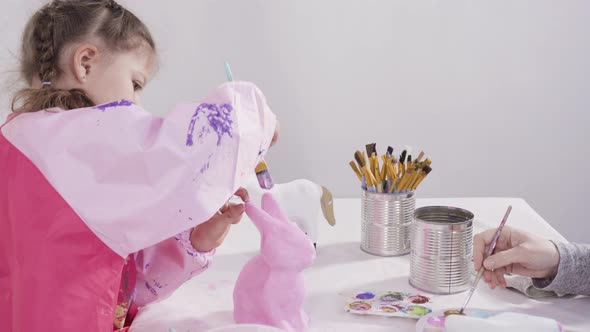 Little girl painting paper mache figurines with acrylic paint  for her homeschooling art project