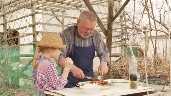 Grandfather and Granddaughter Taste Grilled Meat Kebab From the Grill Grate