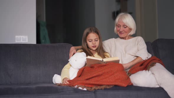 Long-haired girl with her grandmother reading book