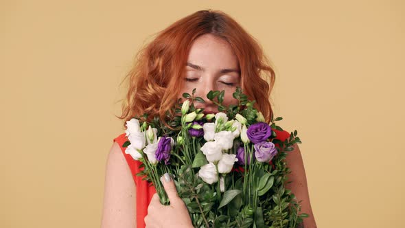 Beautiful Portrait of Young Woman with Ginger Hair Holding Bouquet and Smelling Eustoma Flowers