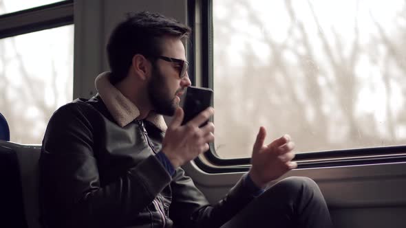 Man In Sunglasses Using Mobile Phone And Call To Friends. Man Talking On Smartphone In Train.