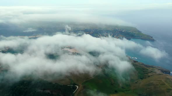 Drone flying over clouds revealing Ajo scenic Coastline, Aerial High view. Cantabria. Spain