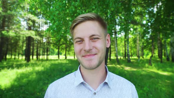 A Young Man Smiling in the Park in Summer