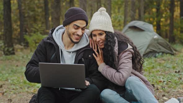 Young Happy Couple in Love Tourists Sit Outdoors in Campsite Look at Laptop Screen Choose Place to