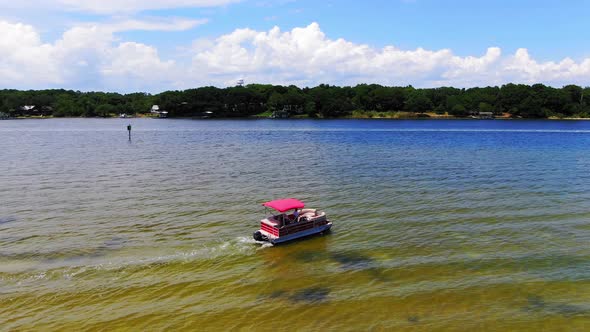 Aerial view panning right of a pontoon boat leaving some small islands near Destin Florida.