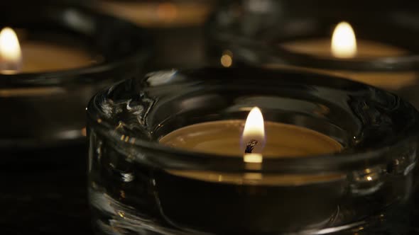 Tea candles with flaming wicks on a wooden background - CANDLES 023