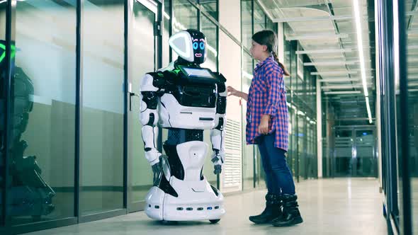 A Girl is Touching a Modern Robot While Chatting with Him