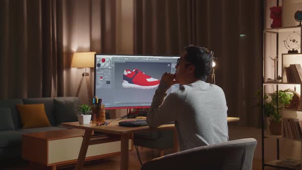Asian Male Footwear Designer Thinking While Designing Shoe On A Desktop At Home