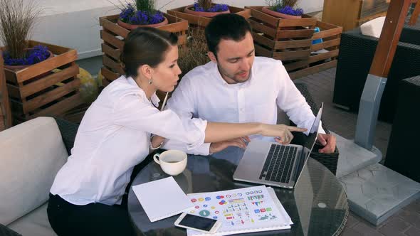 Smiling Businesspeople with Laptop Outdoors in Cafe