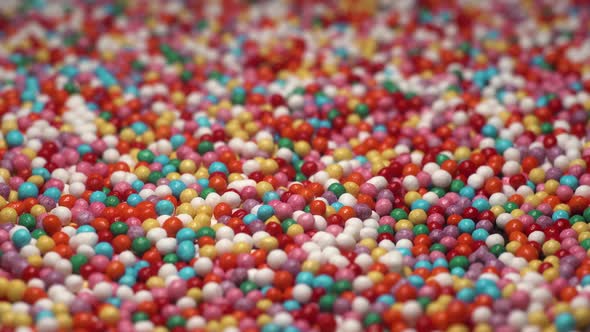 A Lot of Colorful Sprinkles Sugar Candy Lay on Table. Multi-colored Dragee Slow Passing Camera. Red