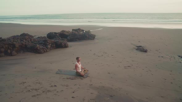 Man Meditating on Sandy Ocean Shore