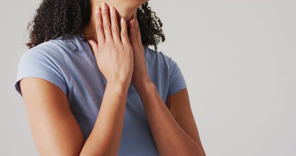 Video of biracial woman touching her neck on white background