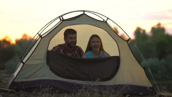 Joyful Couple Zipping Dome Tent and Winking, Preparing to Sleep in Wild, Camp