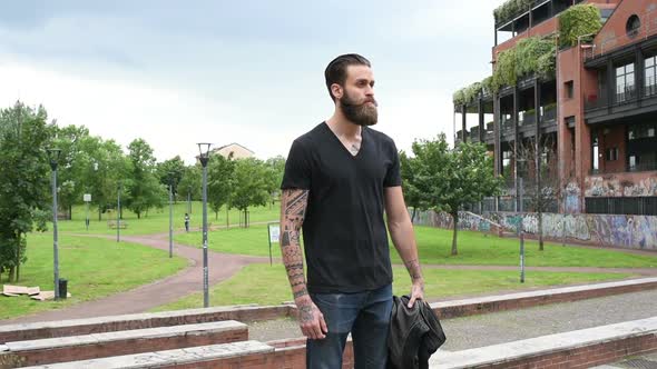 young beautiful bearded man posing outdoor looking away