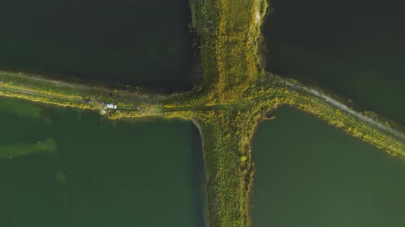 Aerial View Of Cars On Lush Pathway Between Fishponds In The Village Of Frydman In Poland. drone sid