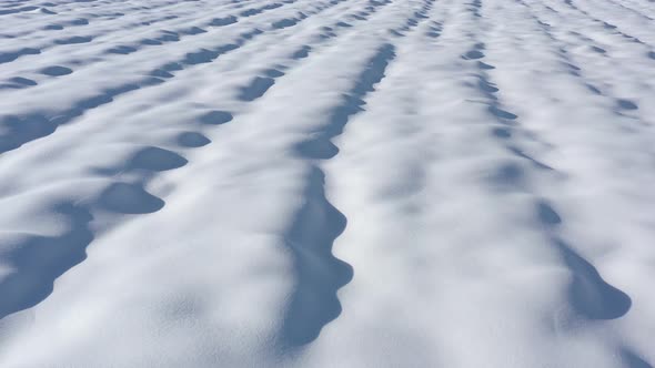 Slow flying over the snow dunes made by wind 4K drone video