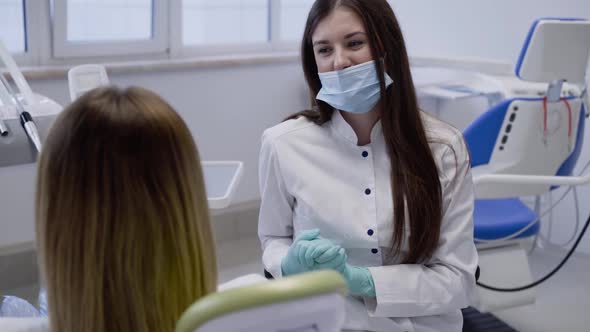 Cheerful Dentist Consulting Female Patient Before Treatment in Clinic