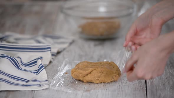 Women's Hands Wrap the Dough in Plastic Wrap