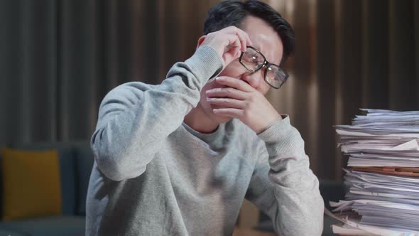 Close Up Of Tired Asian Man Yawning And Taking Off His Glasses Before Sleeping While Working