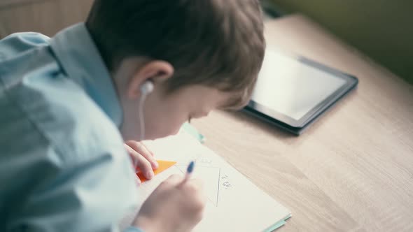 CU Boy Do School Homework Writes Ballpoint Pen in Notebook In the Ears are Inserted Headphones