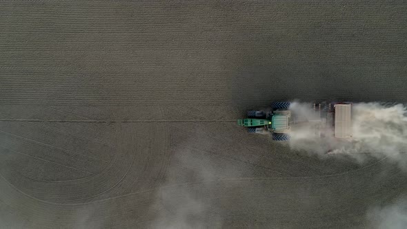 Drone footage of green tractor working in a fields.