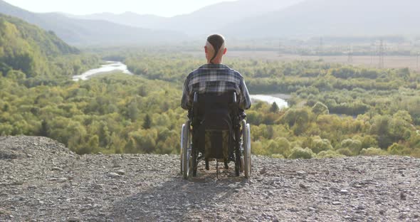 Modern Disabled Man in Wheelchair Which Looking at the Picturesque Nature from Hill