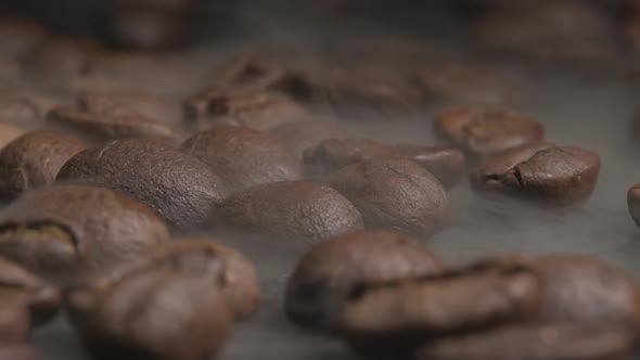 Close up macro shot of roasting coffee beans in a hot oven, thick smoke coming from the beans as the