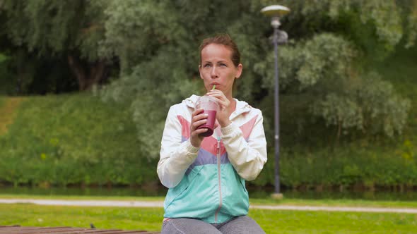 Woman Drinking Smoothie After Exercising in Park