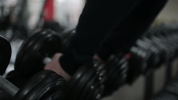 Hands of Strong Male Athlete Taking Heavy Dumbbells during Workout in the Gym