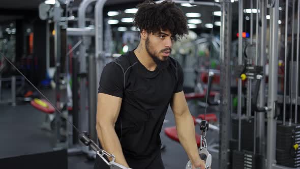 Young Man Exercising on Multistation at Gym for Arm and Shoulders Muscles