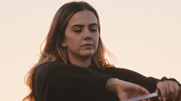 Young Woman with Long Hair Swinging with a Sword Blade on Bright Sunset