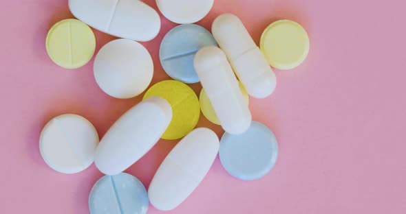 Closeup Rotation  Blue White and Yellow Pills on Pink Background