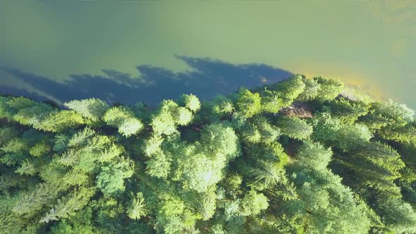 Top down aerial view of big lake with clear blue water between high mountain hills covered