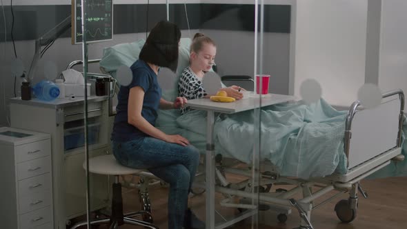 Sick Child Patient Sitting in Bed with Oxygen Nasal Tube Eating Healthy Food During Lunch