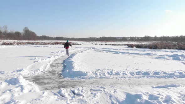 Person rides in white figure skates on frozen lake in winter