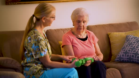 Physical therapist doing a home healthcare visit with an elderly woman showing her how to use weight